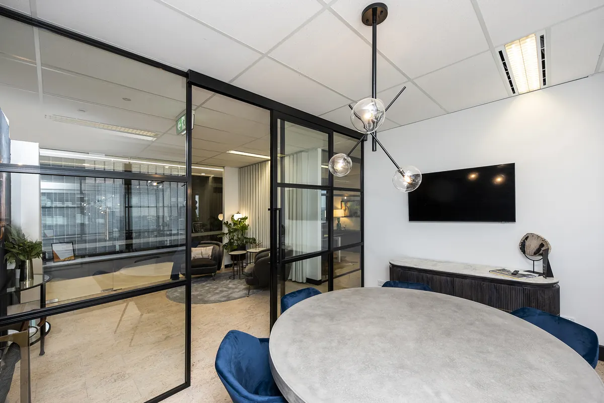 Benchmark office fitout, St Georges Terrace Perth — glazed meeting room with a pendant light and blue velvet chairs.