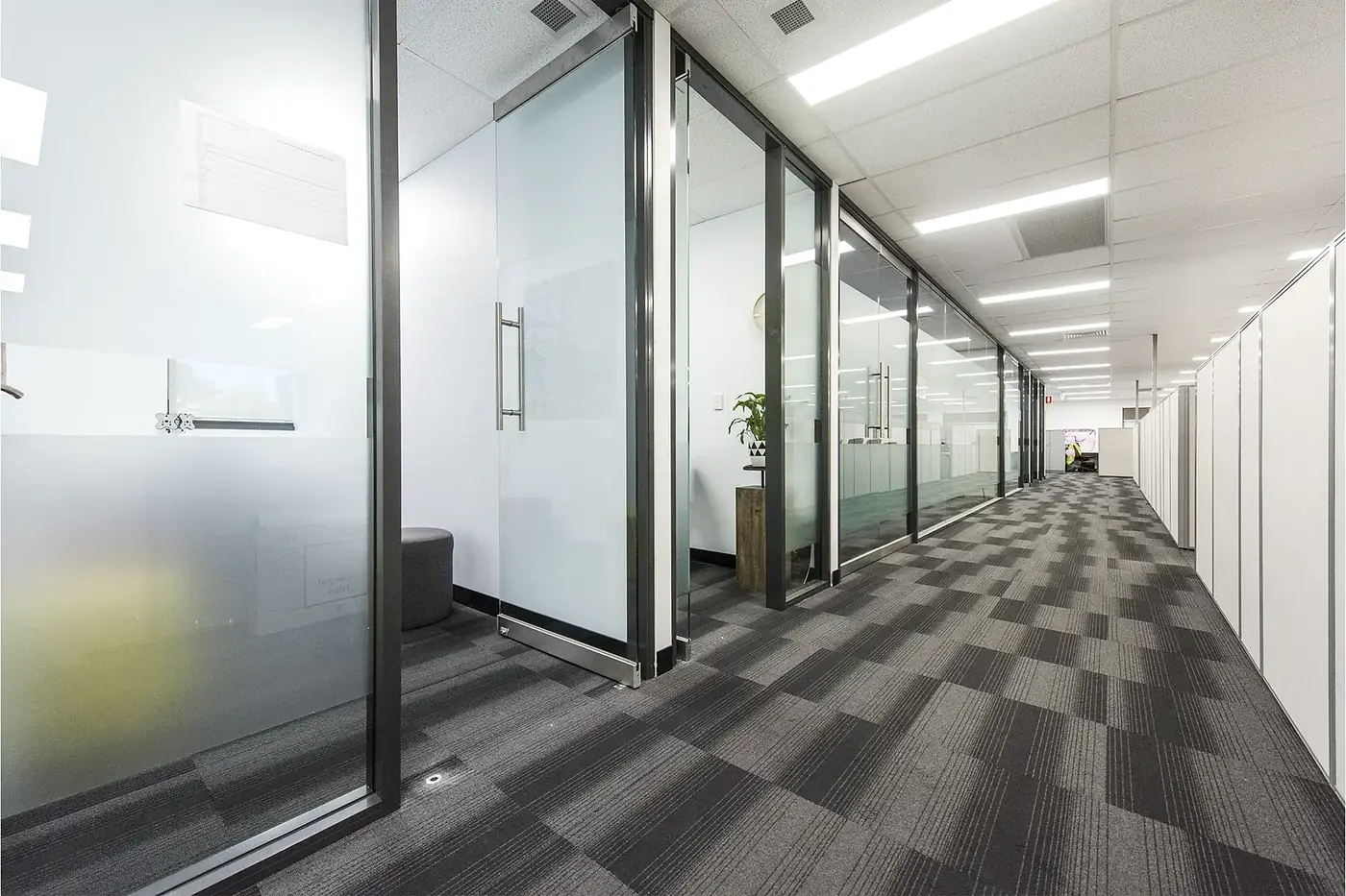 VEOLIA &mdash; office corridor lined with black-framed glazed partitions and frosted meeting rooms.